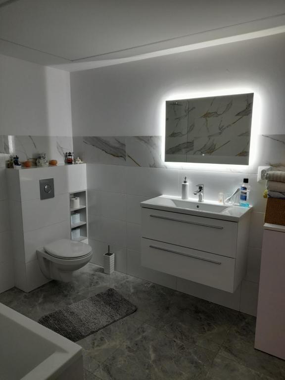 a white bathroom with a toilet and a sink at Malwers in Zielonka