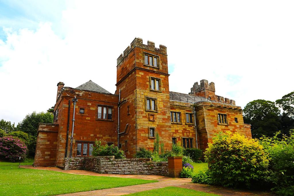 an old brick building with a tower on top at Dalston Hall in Carlisle