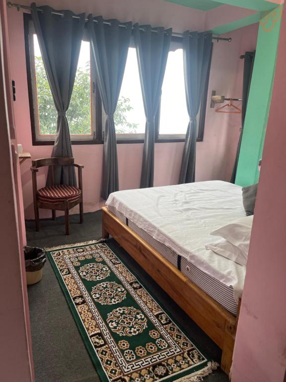 a bedroom with a bed and a chair and a window at The Rainbow Inn in Sonāda
