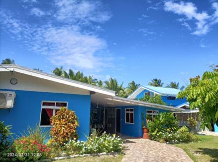 a blue and white house with flowers in front of it at Terai vahine lodge in Rangiroa