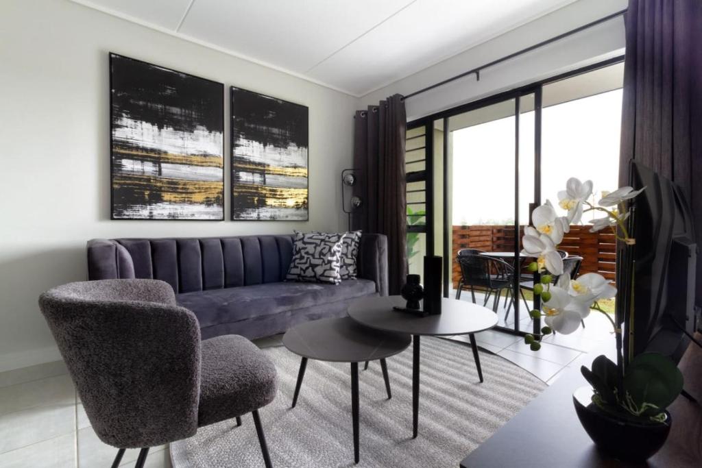a living room with a purple couch and a table at #AlimamaSpaces Pano's Greenpark in Boksburg