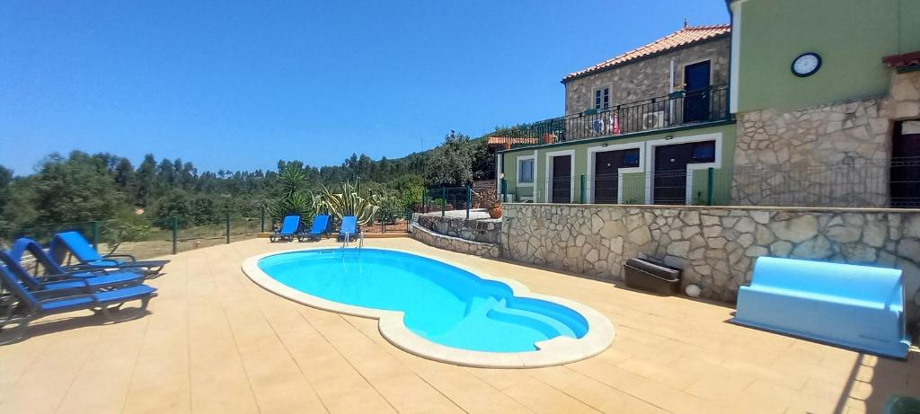 a swimming pool with blue chairs next to a building at Casa De Campo De Oliveiras in Penela