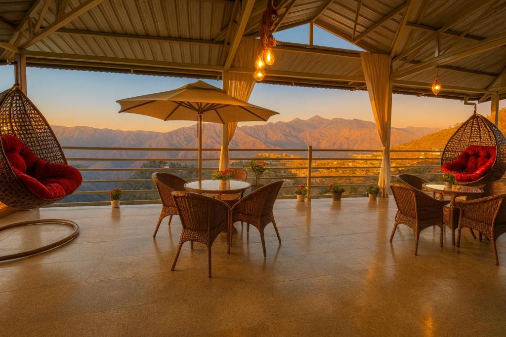 a patio with tables and chairs and an umbrella at The Four Season Resort, Mussoorie - top rated & most awarded property in mussoorie in Mussoorie