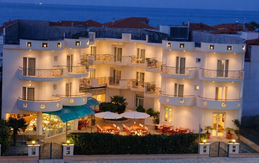 a hotel with tables and umbrellas in front of it at Hotel Filoxenia Beach in Leptokarya