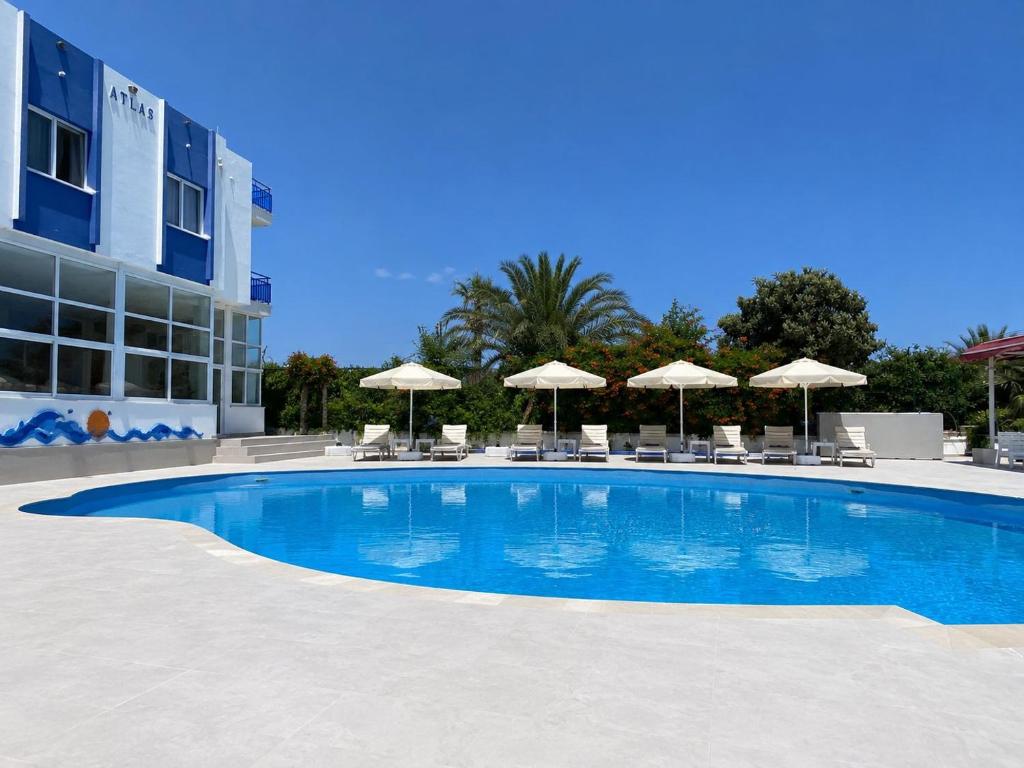 a large swimming pool with chairs and umbrellas at Atlas Butik Otel in Kizkalesi