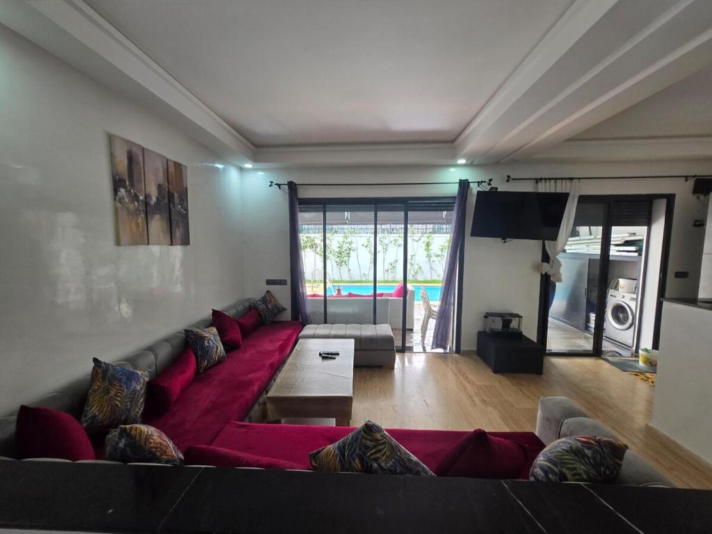 a living room with a red couch in a room at Appartement RDJ in Dar Hamida