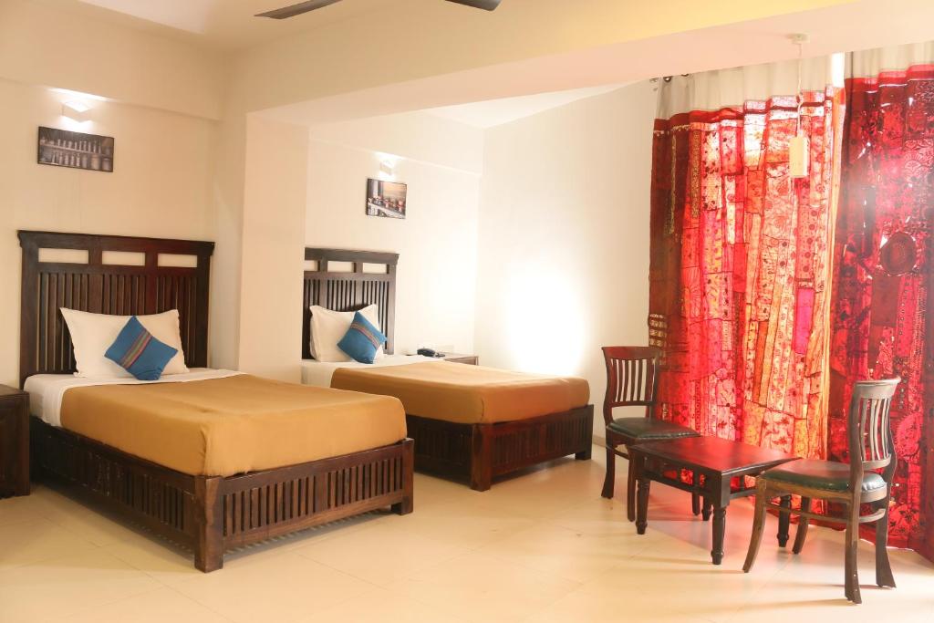 una habitación de hotel con dos camas y una mesa en Hotel Zorba Inn, en Kolhapur
