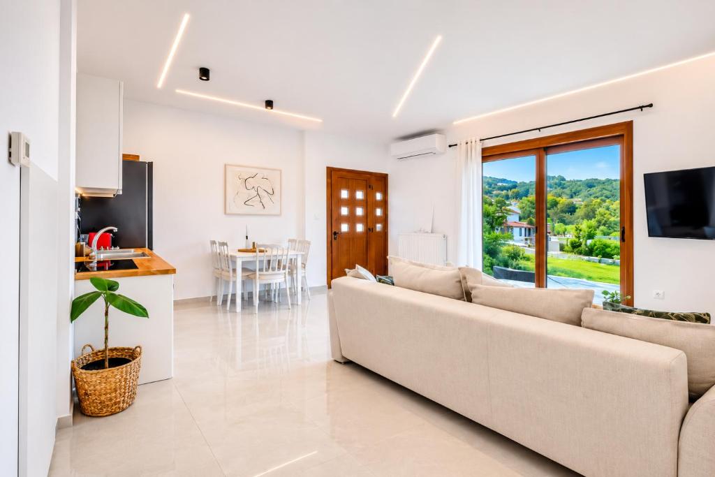 a white living room with a couch and a kitchen at Oasis Acropolis Serres Parking EV Next to Center in Serres