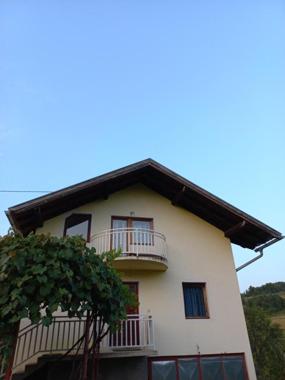 a white house with balconies and a tree at slavko in Šipovo