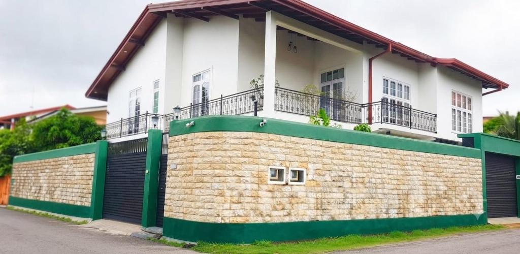a white and green house with a brick wall at Dee Holidays in Moratuwa