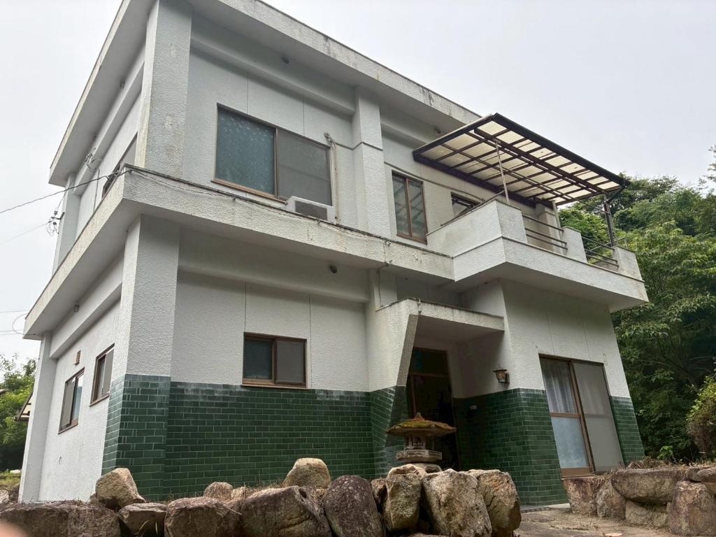 a large white house with a balcony on it at ゲストハウス美和館 in Imabari