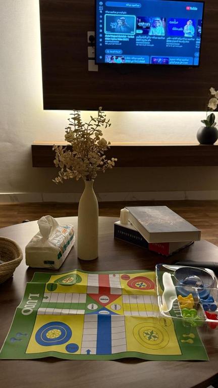 a table with a board game and a vase with flowers at شقة غرفة وصالة مريحة in Jeddah