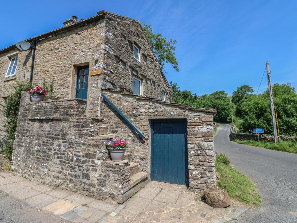an old stone building with a blue door on a road at Wain Wath Cottage in Richmond