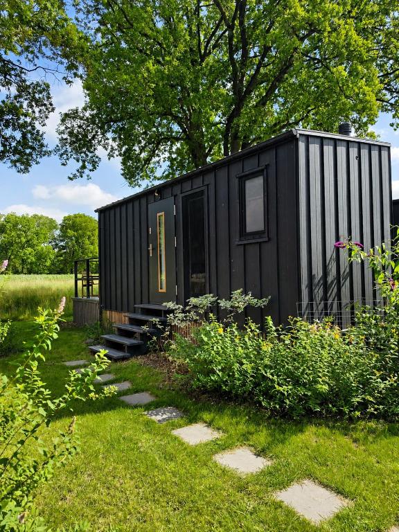 a black tiny house in a garden with stairs at Chalet Helsinki in Bleckede