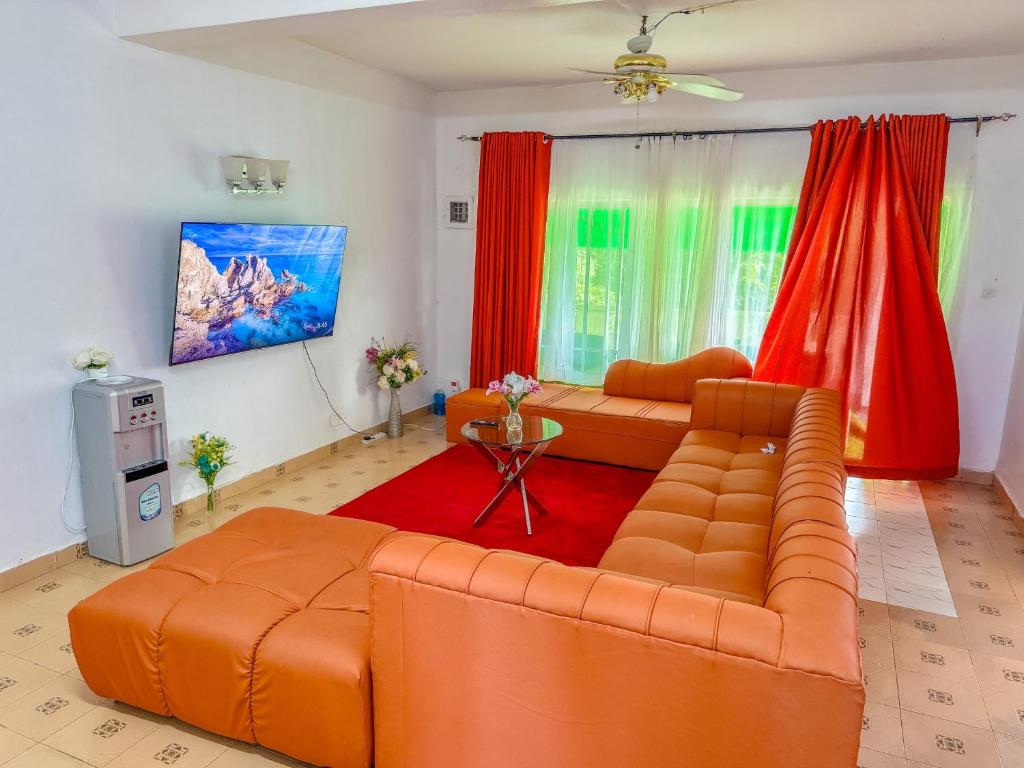 a living room with an orange couch and red curtains at Oceana Villa in Mombasa