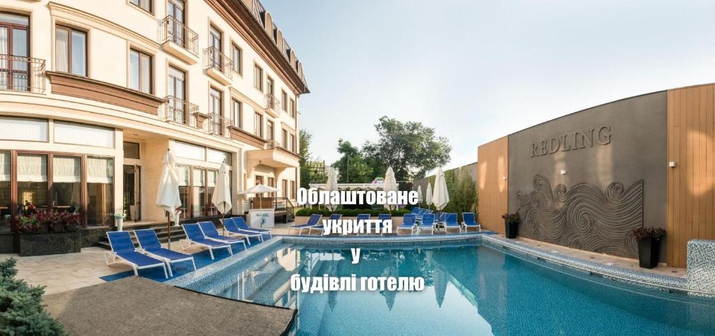 ein Hotelpool mit blauen Liegestühlen und ein Gebäude in der Unterkunft Redling Hotel in Odessa