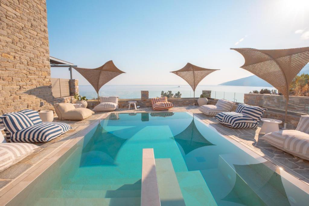 a swimming pool with lounge chairs and umbrellas at Sofrano Luxury Apartments in Evdilos