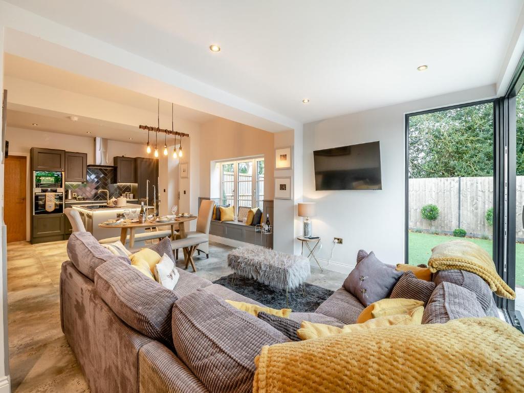 a living room with a large couch and a kitchen at Foreman's Cottage in Skidby