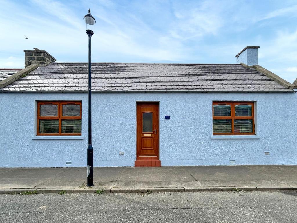 a blue house with a red door on a street at Broadsea Cottage in Fraserburgh