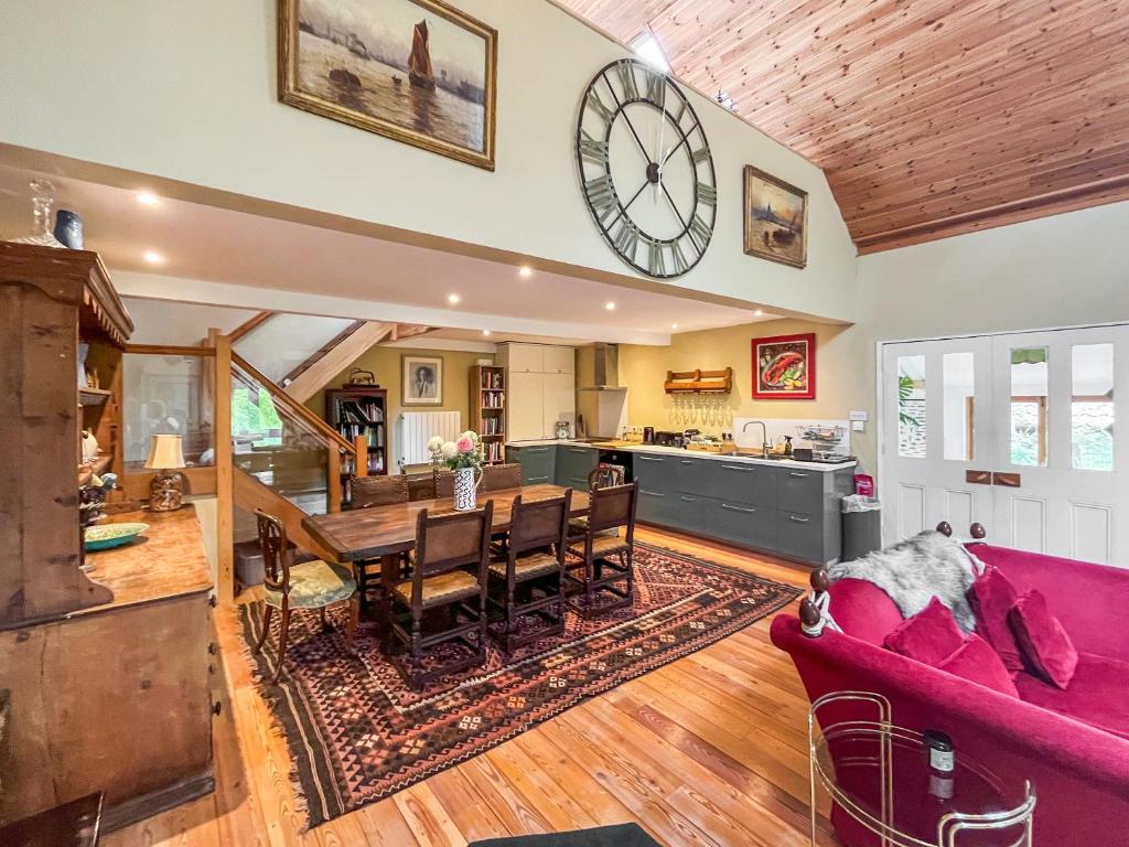 a kitchen and living room with a clock on the wall at Munns Farm Barn in Earls Colne
