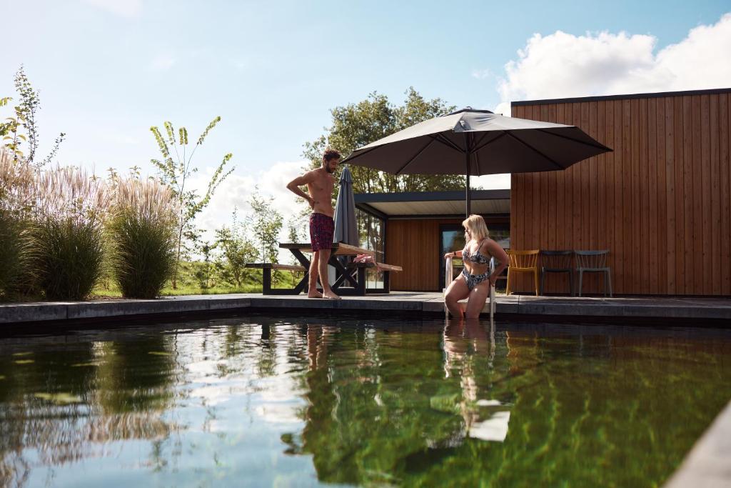 a man and a woman in a swimming pool with an umbrella at Hofparken Wiltershaar in Winterswijk