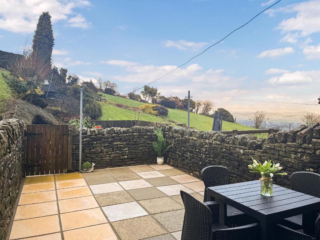 a patio with a table and a stone wall at Quarry Cottage in Barnoldswick
