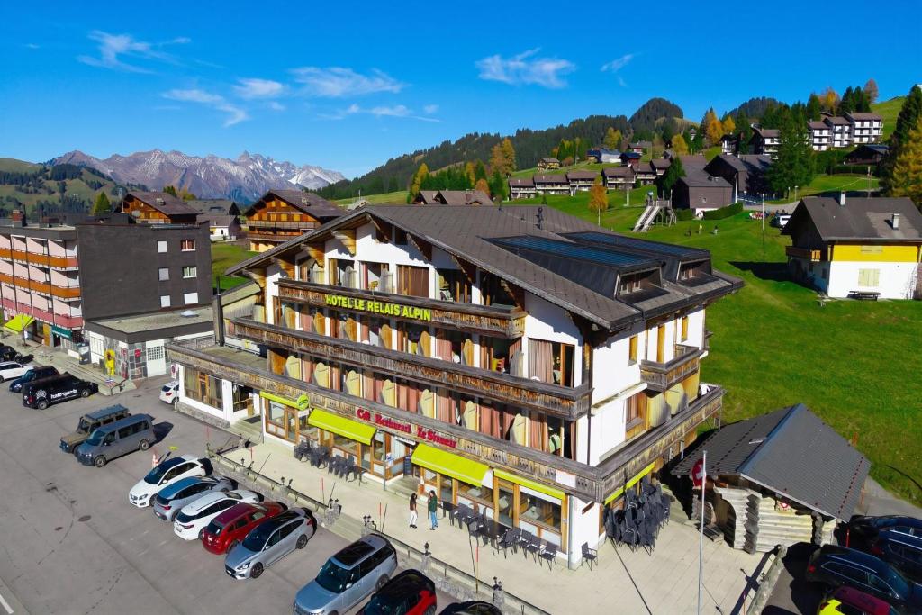 a large building with cars parked in a parking lot at Hotel Relais Alpin in Les Mosses