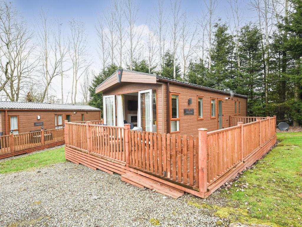 a cabin with a wooden fence in front of it at Marlow Lodge in Hyssington