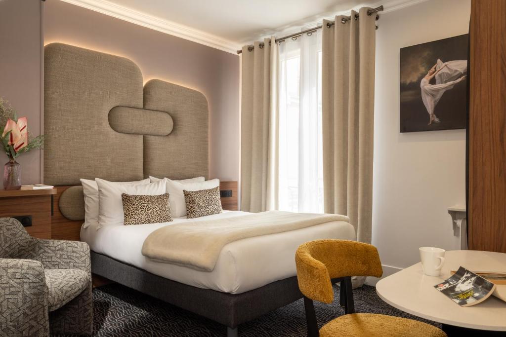 a hotel room with a large bed and a chair at Hotel London in Paris