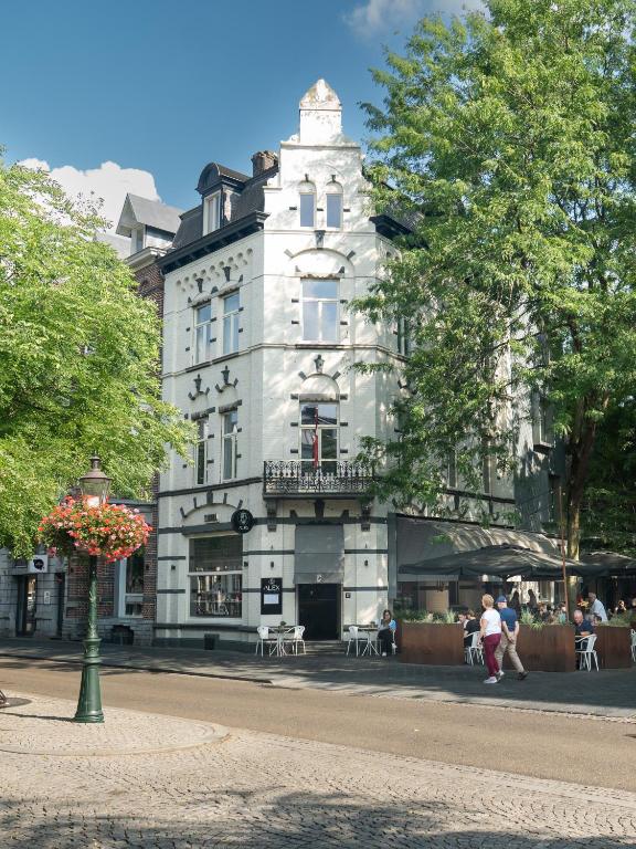 a tall white building with a balcony on a street at Alex Maastricht in Maastricht