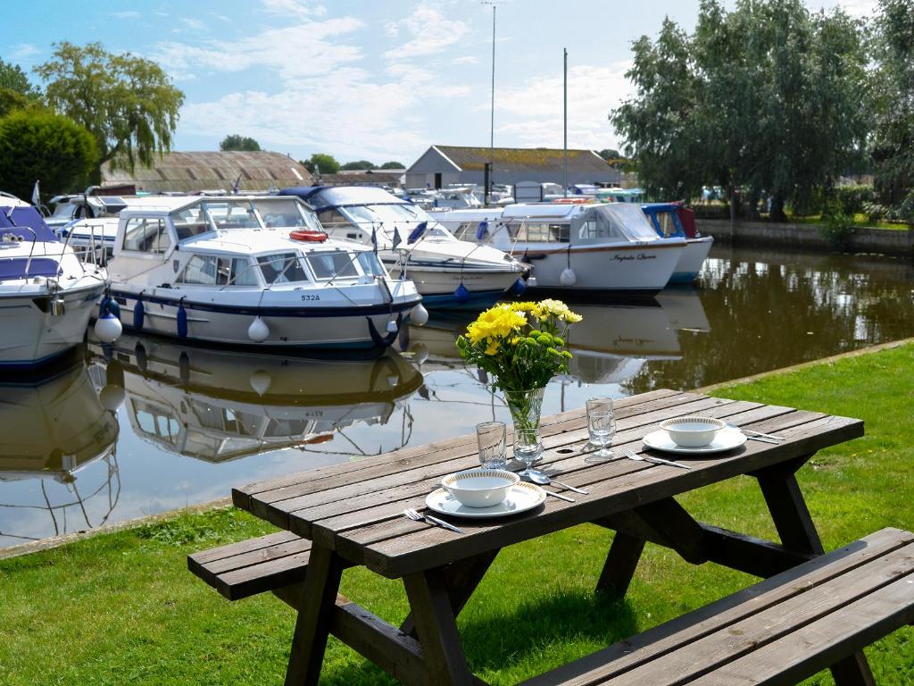 a picnic table with flowers and boats in a marina at Ardea - Uk12695 in Stalham