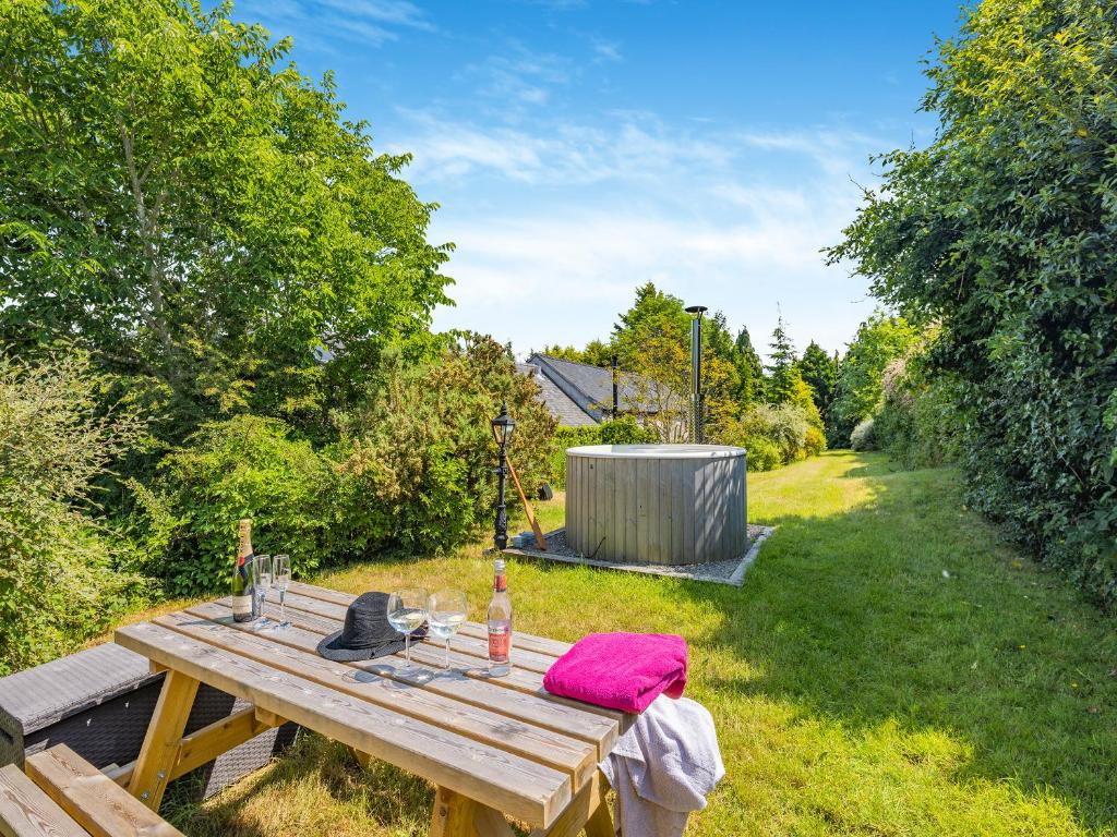 a wooden picnic table with a bottle of wine on it at Bluebell Cottage - Ukc6676 in Bettws-yn-Rhôs