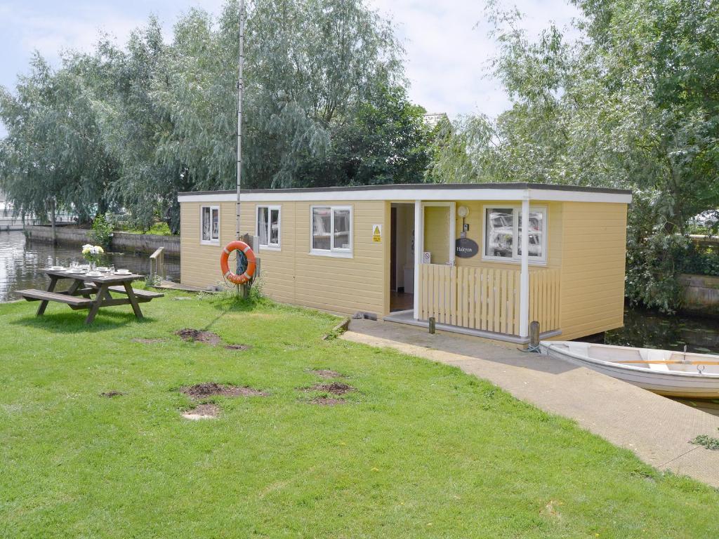 a small yellow house with a picnic table in the grass at Halcyon - Uk12696 in Stalham