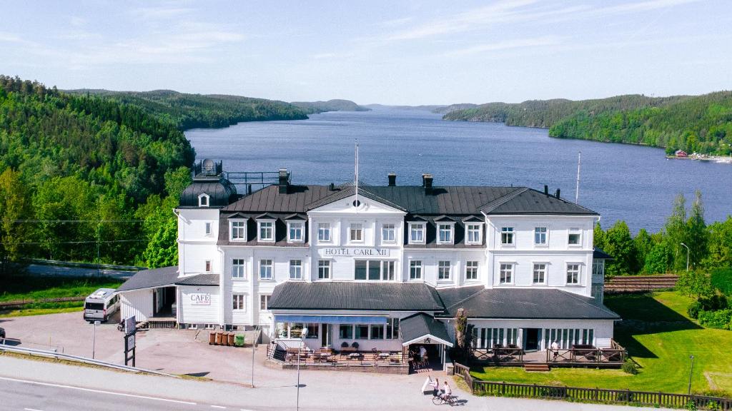 a large white building with a lake in the background at B&B Carl XII in Ed
