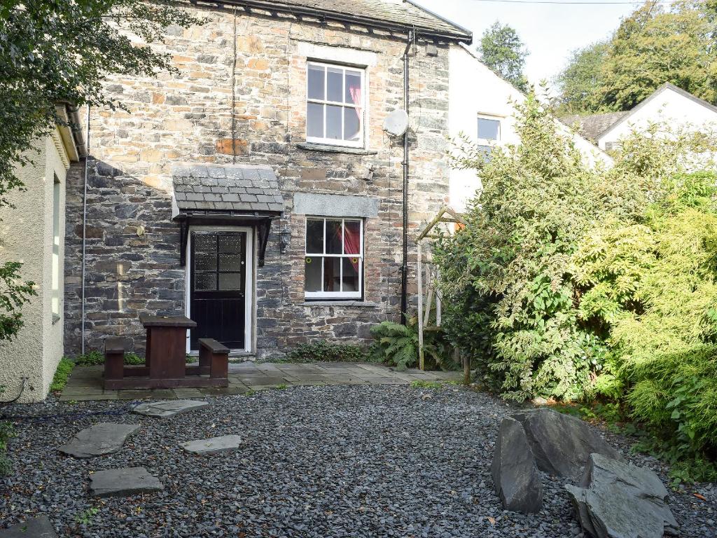 a stone house with a bench in front of it at Croft Cottage in Braithwaite