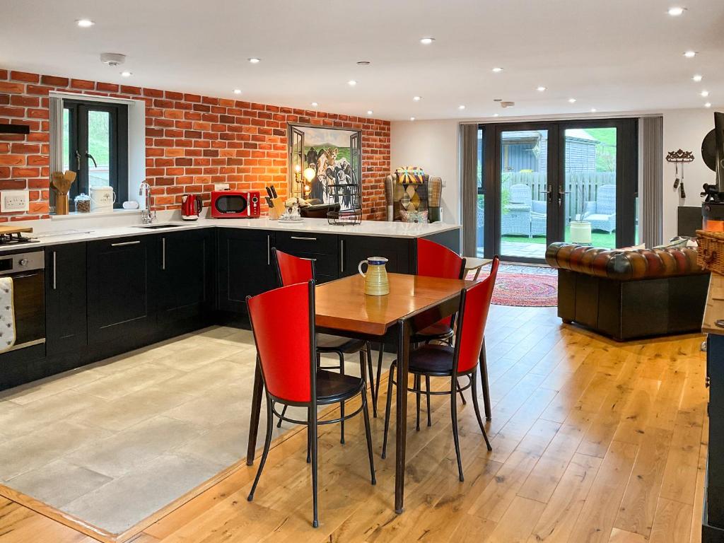 a kitchen with a wooden table and red chairs at Carreg Gwenlais Barn in Carmel