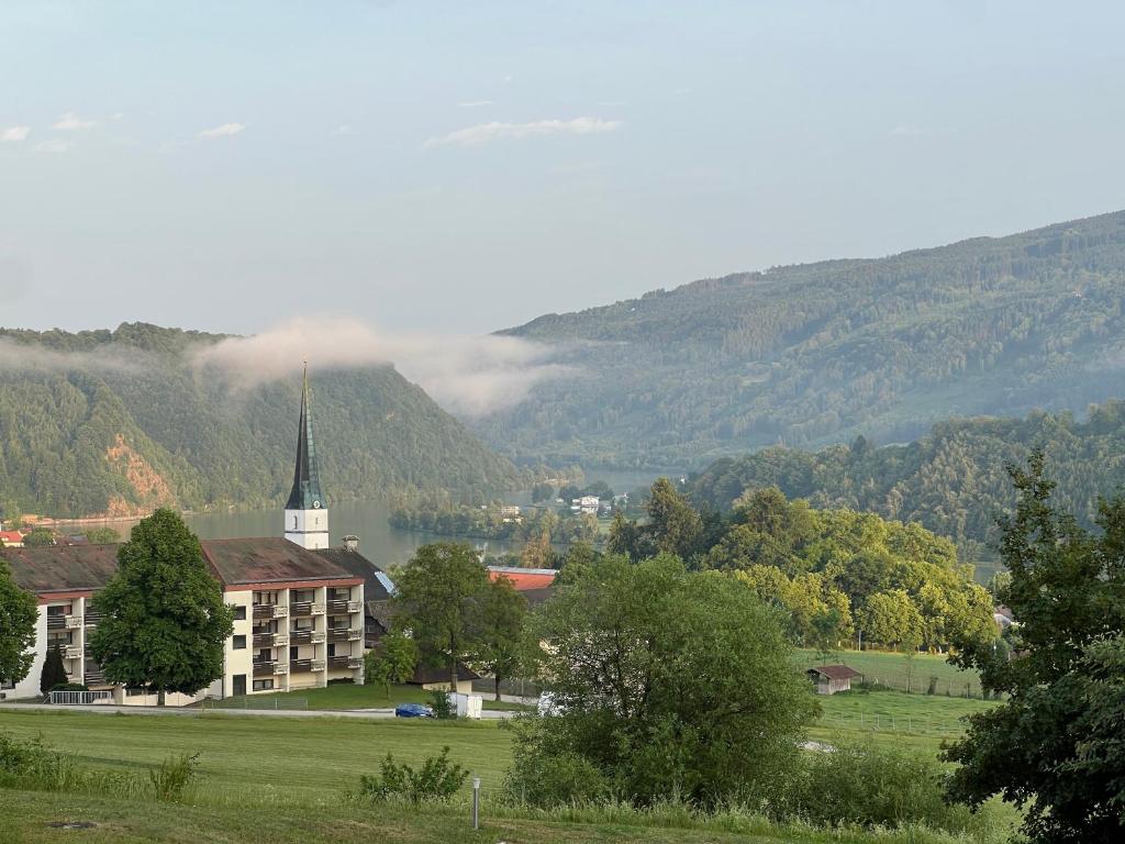 a building in a field with a church and a mountain at Gemütliche Ferienwohnung mit Blick auf die Donau in Obernzell