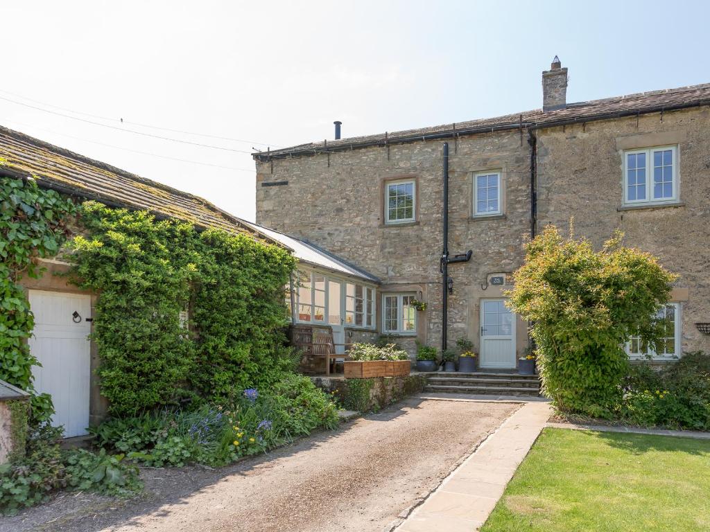 an old brick house with a white door and ivy at The Barn - Uk2475 in West Witton