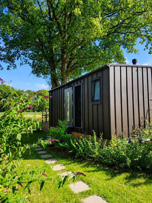 a black tiny house in a garden with a tree at Chalet Oslo in Bleckede