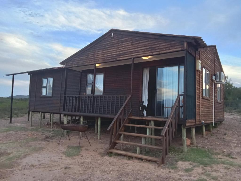 a log cabin with a porch and a balcony at Bietjierus Guest Cottage in Twee Riviere