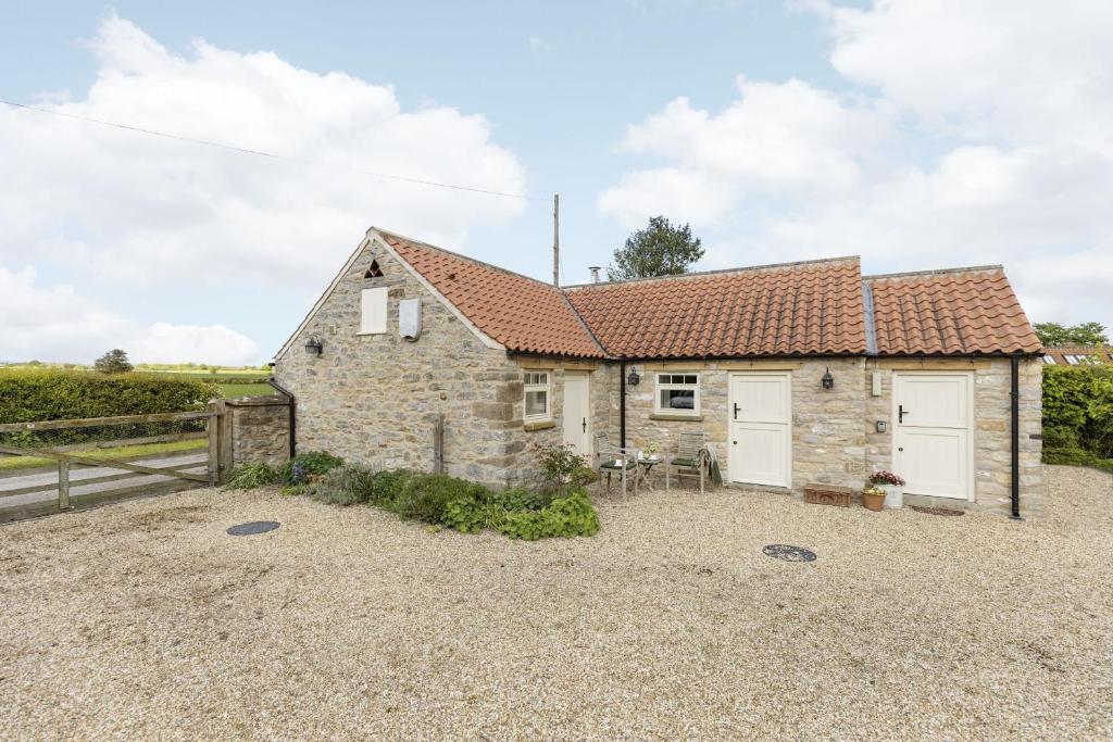 a stone cottage with two white garage doors at Applewood in Harome