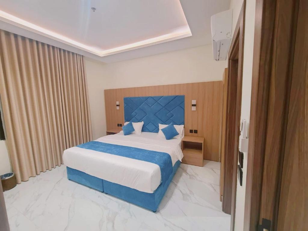 a bedroom with a large bed with a blue headboard at الديار الفاخرة للشقق المخدومة - جيزان in Jazan
