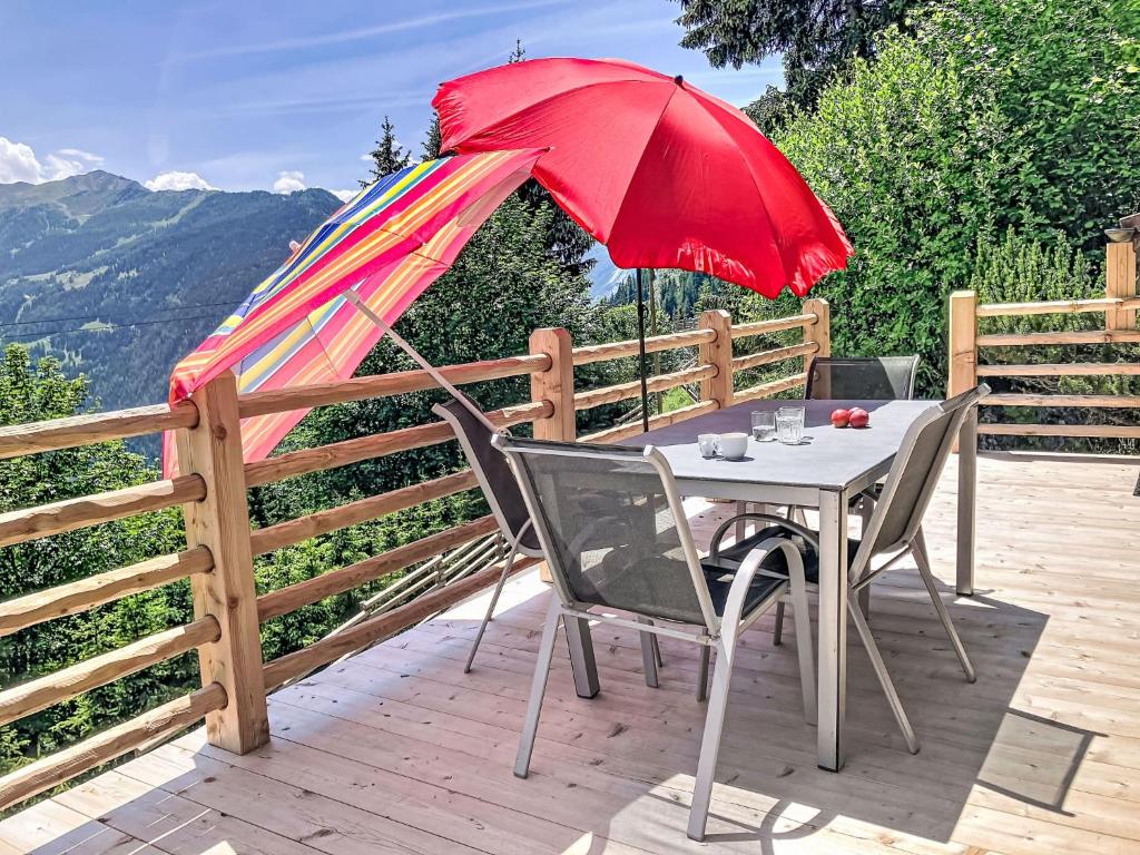 a table and chairs with a red umbrella on a deck at Chalet Château Lapin by Interhome in Verbier