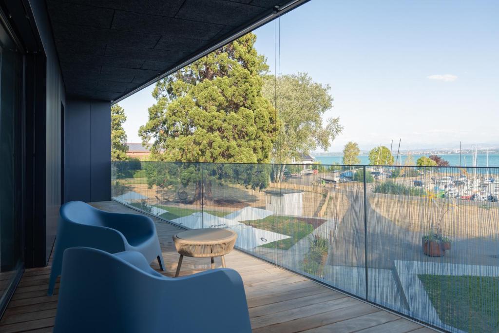 ein Zimmer mit Balkon, blauen Stühlen und einem Tisch in der Unterkunft Pattùs Hôtel in Saint Aubin Sauges
