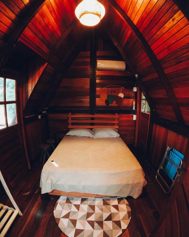 a bedroom with a bed in a wooden cabin at CHALÉ SERINGUEIRA in Outeiro