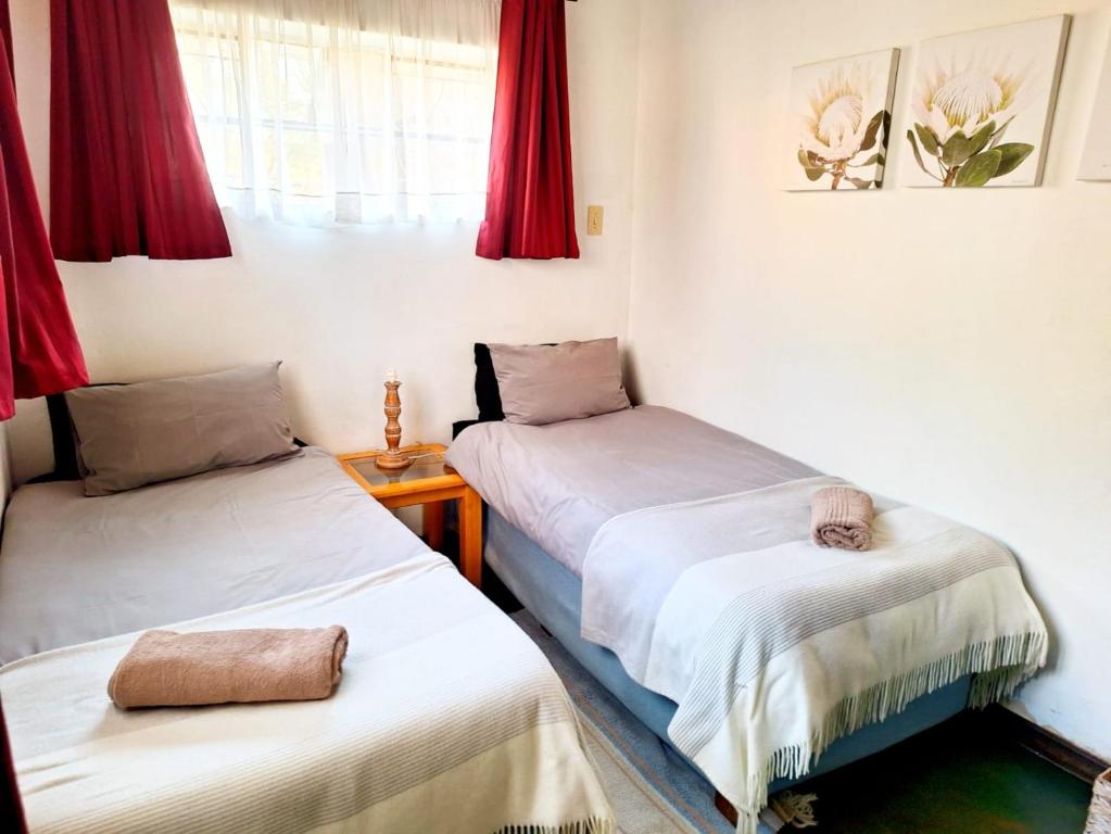 two beds in a room with red curtains at Old Mill B&B in Magaliesburg