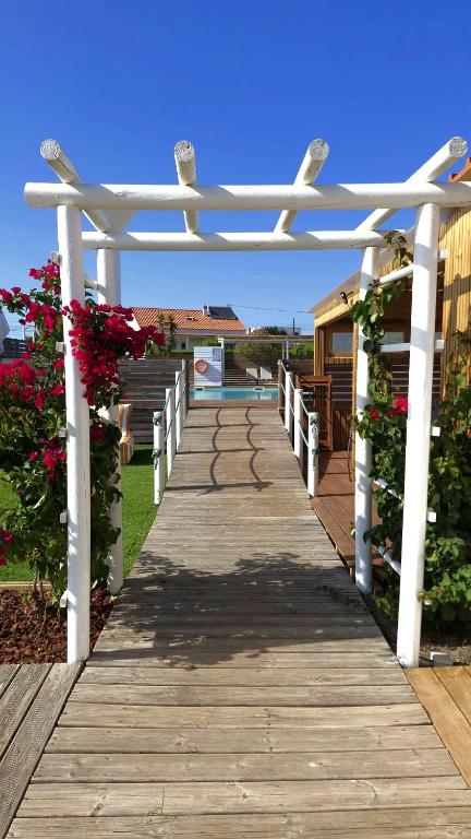 a wooden boardwalk with a white pergola at Casa Amarela in Zambujeira do Mar