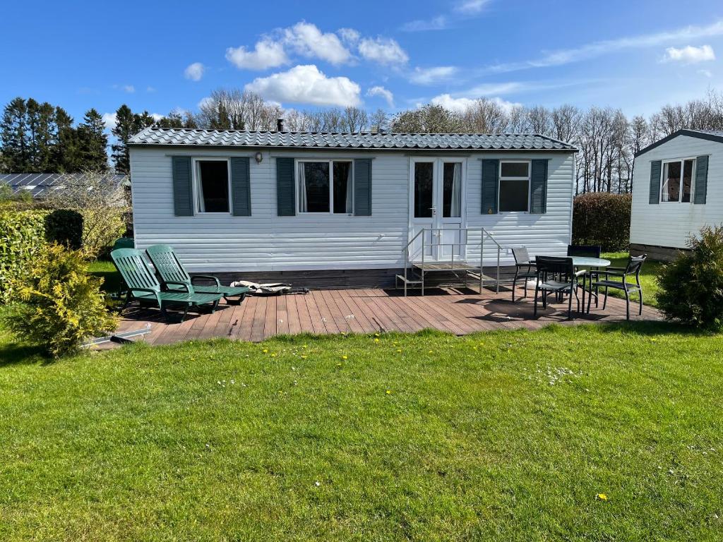 ein Haus mit Terrasse mit Stühlen und einem Tisch in der Unterkunft Camping BuitenRijk - Chalet D36 Huisdiervriendelijk in Valthermond