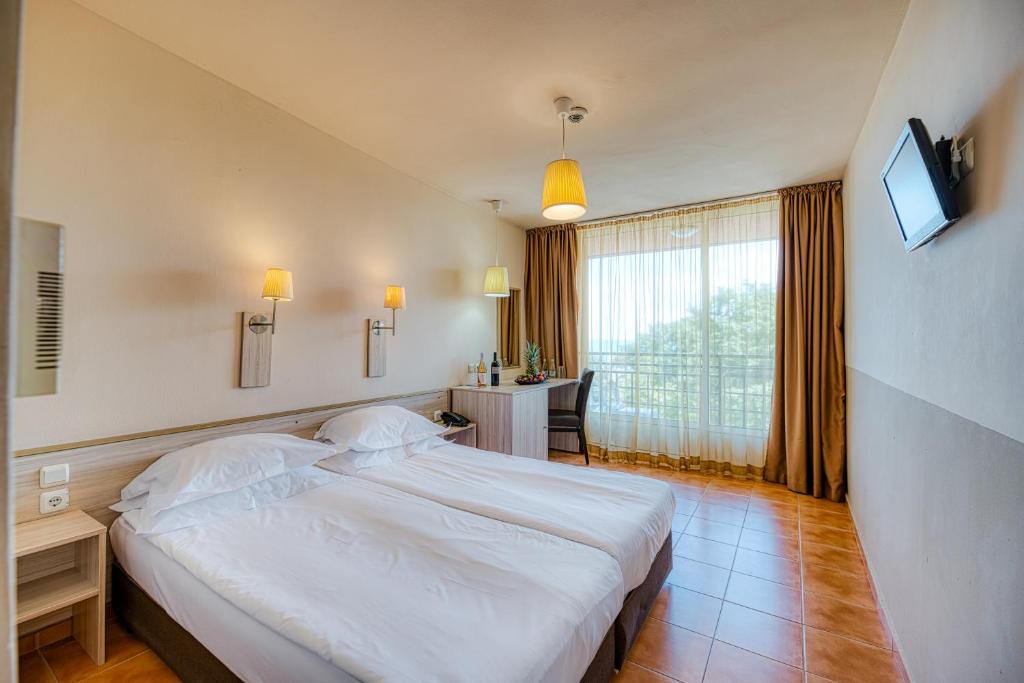 ein Schlafzimmer mit einem großen weißen Bett und einem Schreibtisch in der Unterkunft Gladiola 3-star in Goldstrand