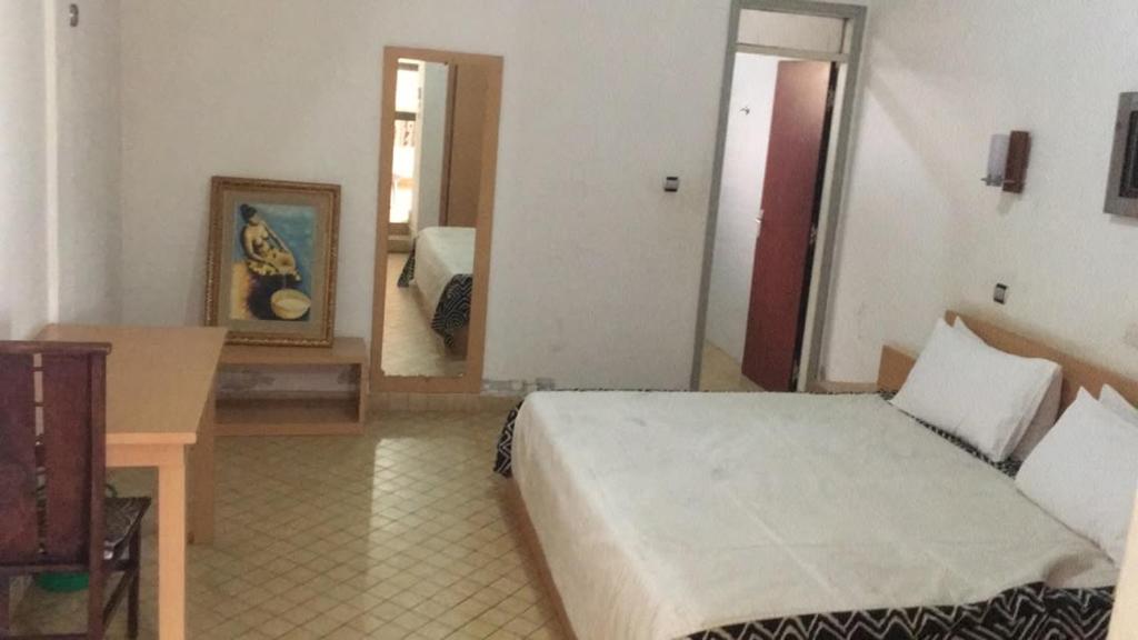 a bedroom with a bed and a table and a mirror at ESPACE iDIMA 2026 in Djérigbé